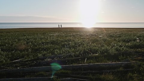 People walk on shore near Kara sea talking. Sunny summer afternoon on Yamal peninsula. Calmness and tranquility.