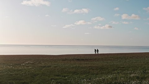 People walk on shore near Kara sea talking. Sunny summer afternoon on Yamal peninsula. Calmness and tranquility.