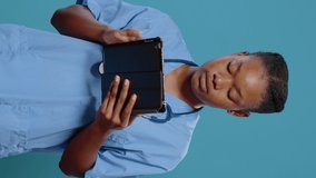 Portrait of nurse working on digital tablet with touch screen to practice healthcare. Medical assistant wearing uniform and stethoscope to treat sickness, using modern device in studio.