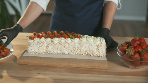 Close-up. The Pastry Chef Puts Fresh Strawberries on a Meringue Cake With Cream. Beautiful Cake Decoration With Cream and Strawberries.
