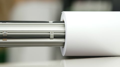 A staff member slides a roll holder into a large white paper roll.