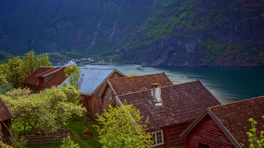 Traditional Norwegian Houses By The Shore Of Aurlandsfjord With Cruise Ship Passing By In Background. Flam Village In Aurland Municipality, Norway. time lapse