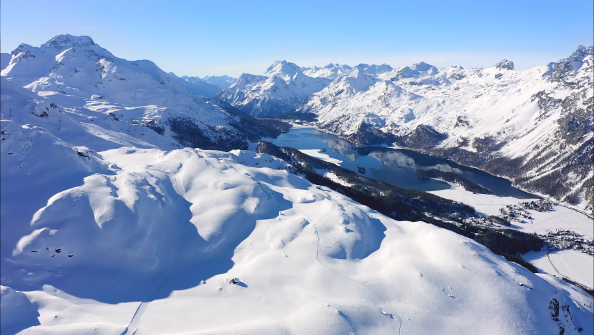 St. Moritz, Switzerland: Aerial view of famous alpine ski resort Saint Moritz in winter Swiss Alps, snow on mountain slopes, Lake Sils on sunny day with clear blue sky - landscape panorama of Europe