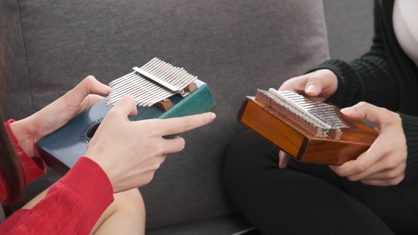 Hands of two lesbian asian women playing wooden kalimba.Lgbt and lifestyle concept.