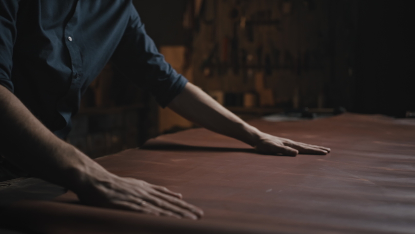 Unrecognizable man tailor smoothing out leather on table, examining fabric quality before work with it, sewing production concept, close up shot Royalty-Free Stock Footage #1081894361