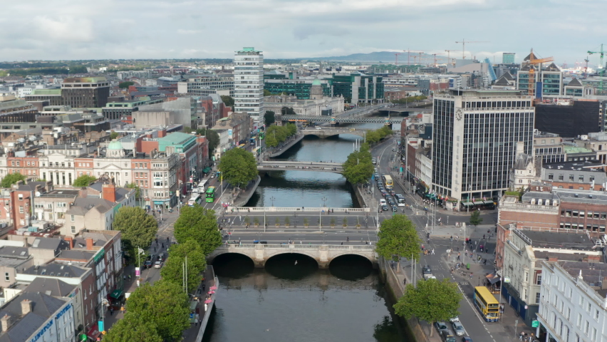 Forwards fly above Liffey river with various bridges. Vehicles driving across river. Dublin, Ireland