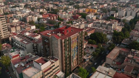 Aerial view of various buildings in housing estate. Drone flying forward and camera tracking tall residential building with flat red roof Mexico City, Mexico