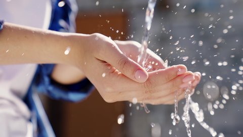 a man with white skin washes his hands with water close-up in the summer, skin hygiene and protection from coronavirus, wash his fingers, stop the spread of bacteria, splashes and drops fly bokeh