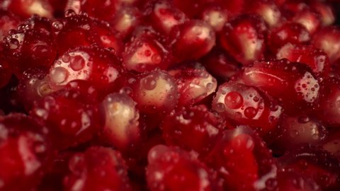 Pomegranate grains for decorating dishes and soft drinks. Transparent drops of water flow from the grains of the pomegranate. Fresh fruit grown on the farm. High quality. 4k footage.