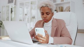 African American business woman holds smartphone use pc at workplace, verification project stats financial data sales charts on laptop and cellphone. Report preparation, synchronization for safety. - Powered by Shutterstock - Get 15% off with code: PIKWIZARD15