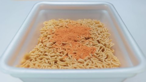 Slow motion. Spices for instant noodles fall from top to bottom into the container with the product.  The ingredients are attached to the noodles in a special package in the set. Brewing noodles.