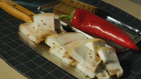 Juicy pork lard in slices with black bread, red pepper and coriander