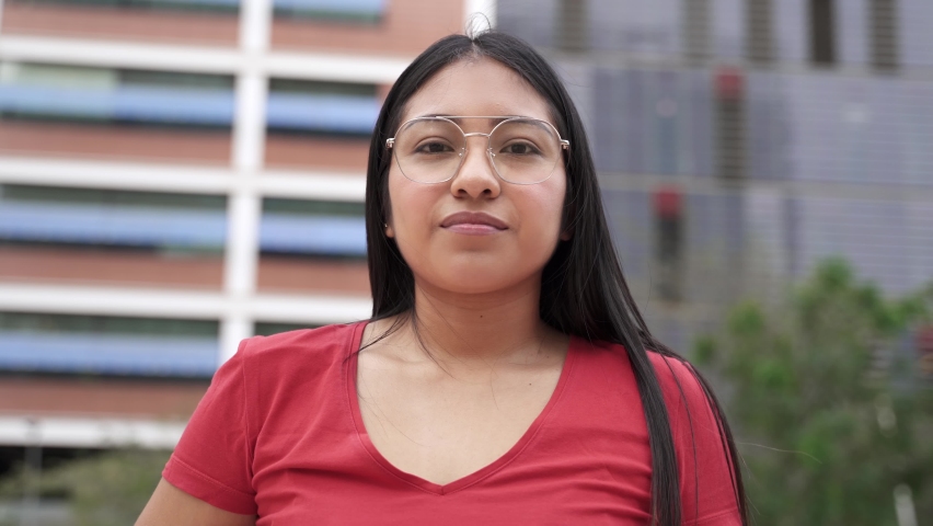 Portrait of carefree Hispanic Latin American Young Woman smiling in the city. Modern Female student girl from Andean Ethnicity (Ecuador, Peru or Bolivia) Royalty-Free Stock Footage #1081920359