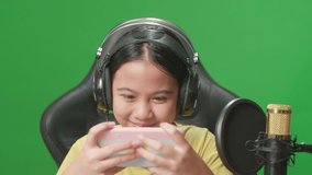 Asian Kid Girl Playing Video Game With Mobile Phone Then Celebrating While Live Stream On Green Screen 

