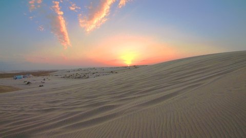 TIME LAPSE at sunset in the desert sand dunes of Qatar and Saudi Arabia. Khor Al Udeid, Persian Gulf, Middle East. Discovery and adventure travel concept.