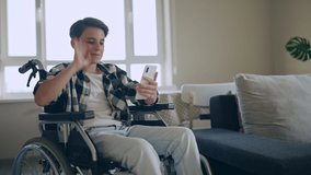 Schoolboy with disability talking to friend by video call, sitting in wheelchair