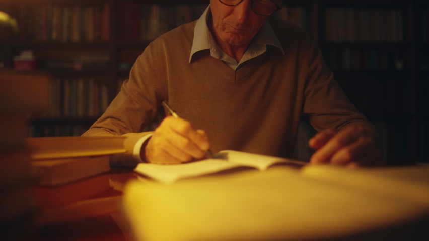 Senior scientist working in library, writing notes in the evening, freelance Royalty-Free Stock Footage #1081923299