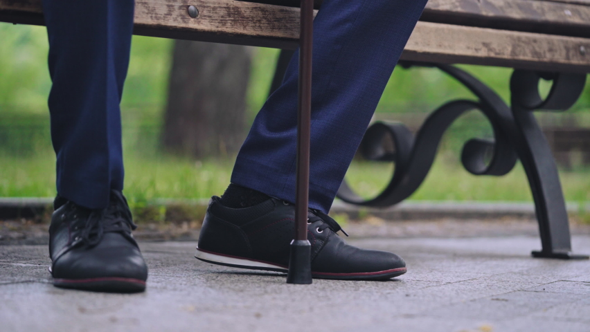 Lonely elderly male sitting bench in park, leaning on walking cane, depression | Shutterstock HD Video #1081923551