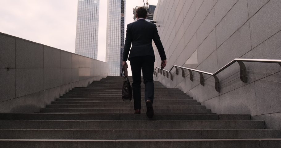 camera moves up. rear view. man walking up the stairs. Business people walking up steps Pedestrian Businessman Walking Out Of Metro. Ambitions concept with man climbing stairs. success business step Royalty-Free Stock Footage #1081928219