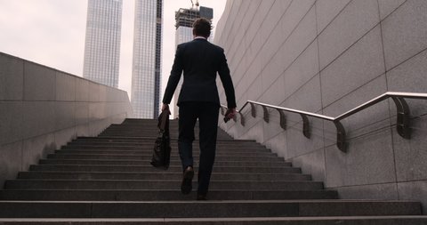 camera moves up. rear view. man walking up the stairs. Business people walking up steps Pedestrian Businessman Walking Out Of Metro. Ambitions concept with man climbing stairs. success business step