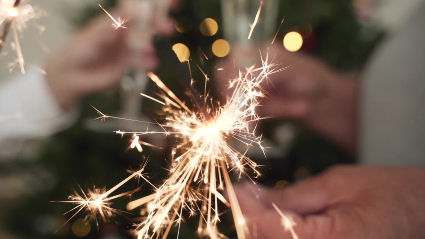 Slow motion two cheerful women with sparklers for Christmas with glasses of champagne and lights on the background. Happy new year. Christmas night. Happy family and celebrate