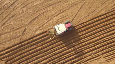 The farmer, who prepares his field for the new crops to be planted in October with a tractor, is plowing his field. Aerial shot of a farmer planting crops in a field.