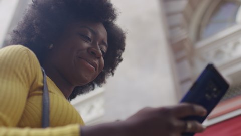Camera moves around an attractive black female smiling as she uses her phone, in slow motion