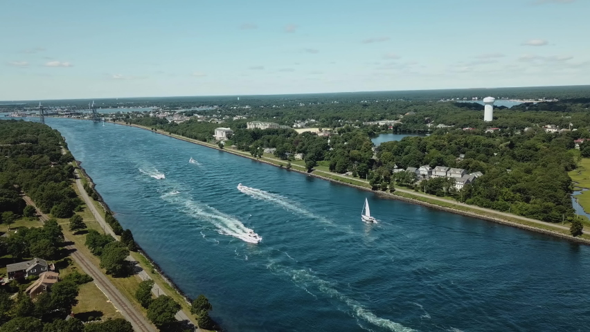 A beautiful sunny day on the Cape Cod Canal: a view of a remote railway bridge. White boats and yachts sail on blue water. Shooting from a drone from a bird