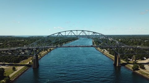 The beautiful Bourne Steel Bridge in Bourne, Massachusetts.  Cars drive over the bridge on a sunny day. Shooting from a drone flying under a bridge.