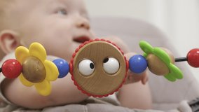 Cute baby rocking himself in a rocking chair, 7 month old caucasian toddler relaxing in infant bouncer, child face close-up. High quality 4k footage