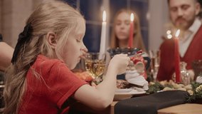Little girl eating at the dining table on Christmas Eve, dressed up in red. Family gathering for Christmas celebration. High quality 4k footage - Powered by Shutterstock - Get 15% off with code: PIKWIZARD15