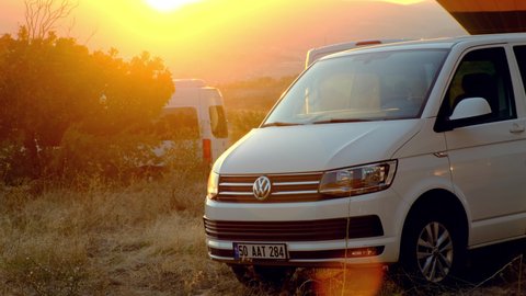 gerime turkey - CIRCA 2021: Volkswagen multivan stands in nature against the backdrop of sunset and balloons. Beautiful sunrise with a white van in the foreground.
