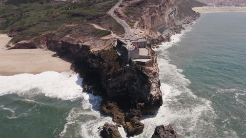 Aerial high angle view of clifftop Fortress of Saint Michael the Archangel and Nazare lighthouse.