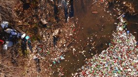 Drone flies over household waste on the shores of forest lake. Bird's eye view. Carpathian mountains, Ukraine, Europe. Cinematic aerial shot. Environmental pollution problems. Filmed 4k, drone video.