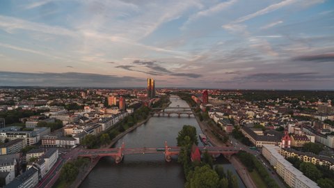 Establishing Aerial View Shot of Frankfurt am Main De, financial capital of Europe, Hesse, Germany, beautiful red light on the buildings, tracking along the river, bridges