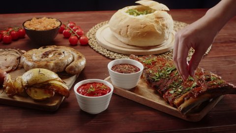 Traditional czech cuisine. Fried sausages, bratwursts, meat with sauce on table, opened soup in bread and adding dill to bbq ribs. Cooked national bohemian food.