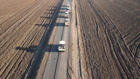 Asphalting a new country long road aerial view. Several asphalt paver rollers drive and tamp the surface, the truck pours the asphalt and people control the work. 4K drone video.