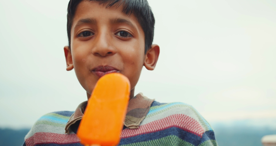 A 4K of a South Asian boy eating orange ice cream  Shimla, Himachal Pradesh, India | Shutterstock HD Video #1081961636