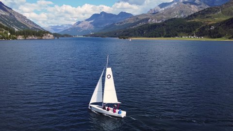 Maloja, Switzerland - August 31 2021: Aerial drone footage of a sailboat that sails on the Sils lake between Maloja and St Moritz in the Engadine valley in Graubunden Canton in Switzerland. 