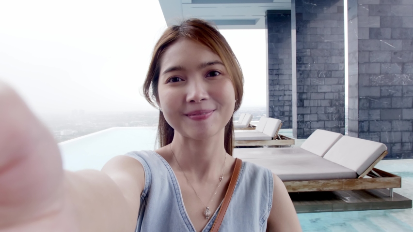 Happy young Asian woman using a smartphone for making selfie and video call on social media, smiling and talking outdoor showing woman lifestyle.