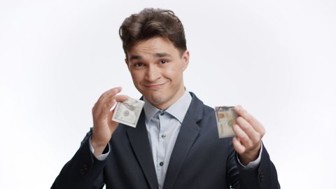 Cashless time. Young wealthy businessman ripping in half banknote and throwing it away, smiling to camera, hinting at digital at crypto money, white studio background, slow motion