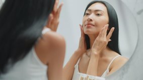 Beautiful Asian Woman Her Perfect Soft Face Skin, Uses Advanced Organic Cream, Smiles in the Mirror. Happy Female Enjoying Her Morning Beauty Routine. Wellbeing, Natural Beauty, Cosmetic Products - Powered by Shutterstock - Get 15% off with code: PIKWIZARD15
