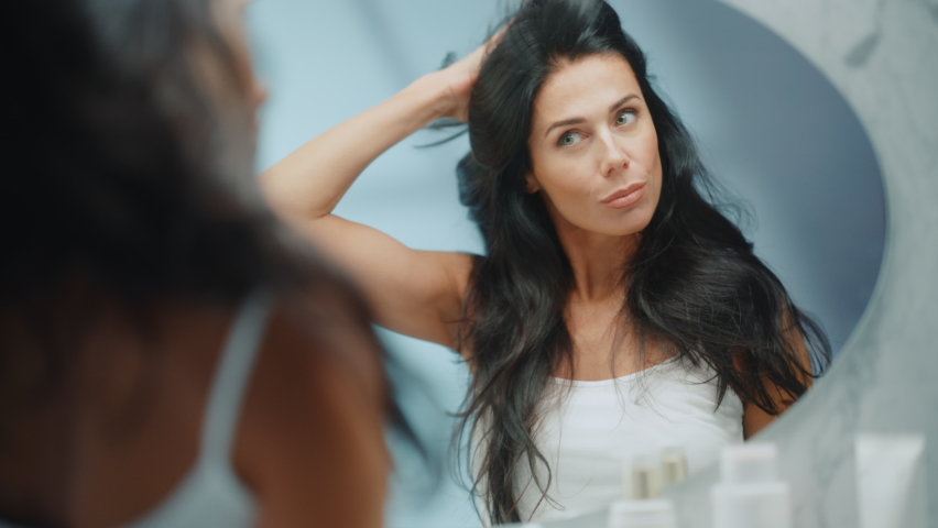 Beautiful Early Middle Aged Woman Looks into Bathroom Mirror Touches Her Lush Black Hair, Admires Her Looks. Concept for Happiness, Wellbeing, Natural Beauty, Organic Skin Care Products | Shutterstock HD Video #1081984019