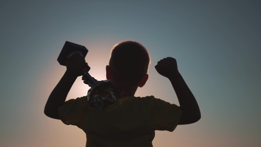 Winner child silhouette. Kid with cup of success raises her hand. Silhouette of child at sunset. Winner success. Victory, path to dream. Child won the victory. Cup in hand of a kid. Superhero kid | Shutterstock HD Video #1081993943