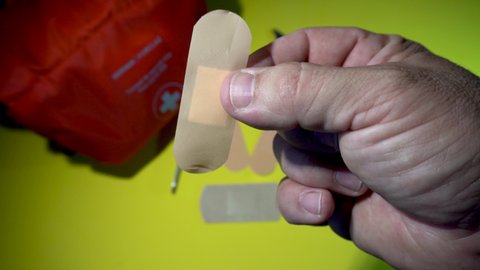 Hand placing a band aid on a finger wound.