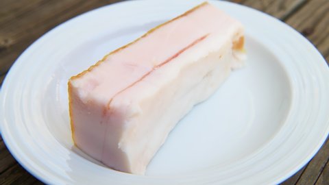 Macro closeup rack focus of traditional salted pork belly fat food for making sandwiches from slices of the lard as traditional Russian cuisine on plate