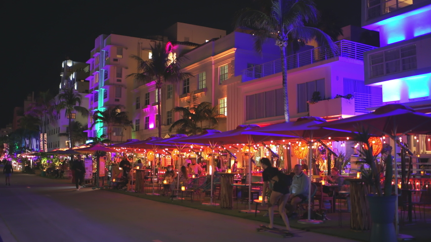 Miami Beach, USA - January 20, 2021: Art deco district at night with neon light sign of La Cerveceria De Barrio Mexican restaurant in South Beach, Florida with people sitting eating dining outside