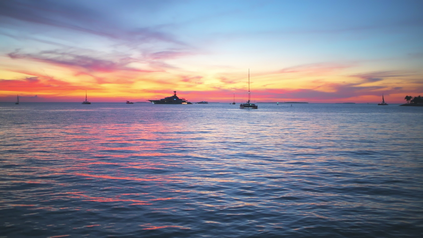 Silhouettes of boats, yachts at colorful sunset twilight blue hour dusk with landscape view on blue cloudy clouds sky by Mallory Square of Key West, Florida