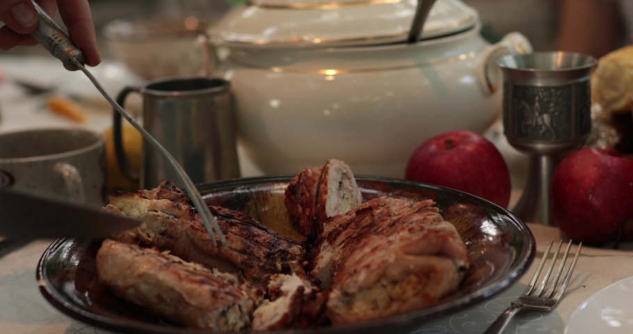 POV hands serve and cut stuffed turkey roll using knife and two prong fork on Thanksgiving dinner table with vintage crockery. Traditional Thanksgiving turkey roulade roasted on grill. Serving dinner