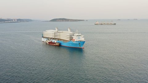 View from the drone of the Rolldock sea heavy load carrier vessel at anchor in the roadstead. The ship carries wind turbine blades. Russian bridge in the background. AUG 18, 2021 VLADIVOSTOK, RUSSIA